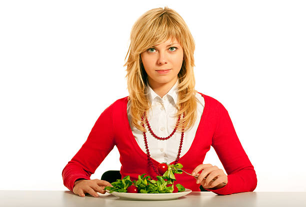 Young women eating green salad.