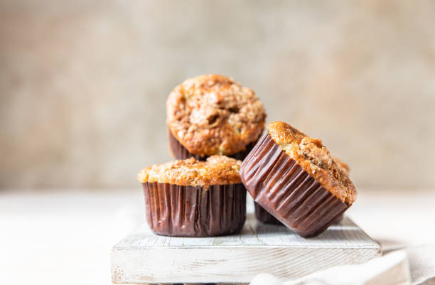 Tasty breakfast muffins with oat crumbs topping on cutting board.
