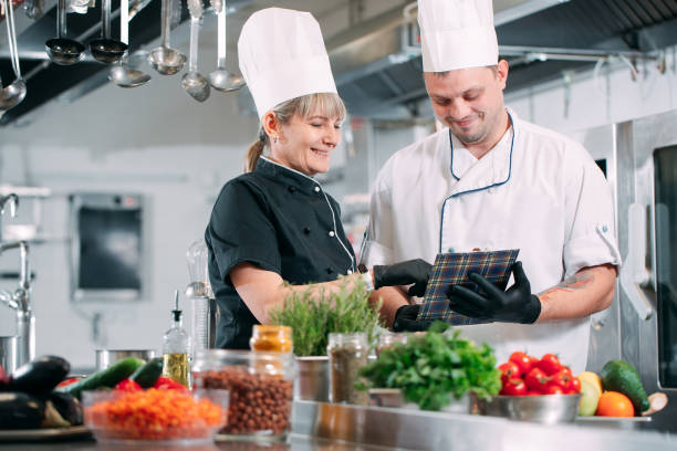 Two chefs discuss the menu in the kitchen of a restaurant or hotel