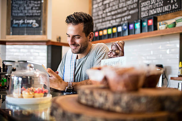 Coffee shop owner using the digital tablet writing the ingredient needs to buy.