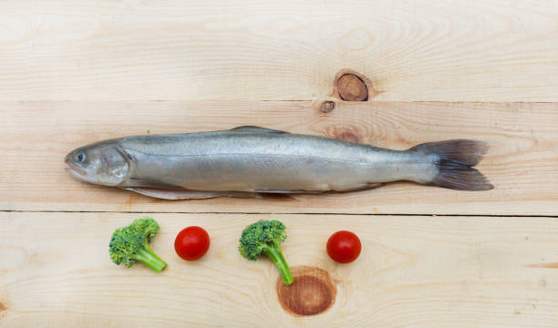Raw rainbow trout river fish on a wooden background with vegetables